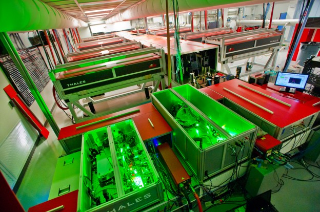 The BELLA laser during construction. In the foreground, units of the front end stretch and amplify short, relatively weak laser pulses before further amplification in the long central chamber. Amplification is done by titanium sapphire crystals boosted by a dozen pump lasers. At the far end of the hall the now highly energetic stretched pulse is compressed before being directed to BELLA’s electron-beam accelerator component. 